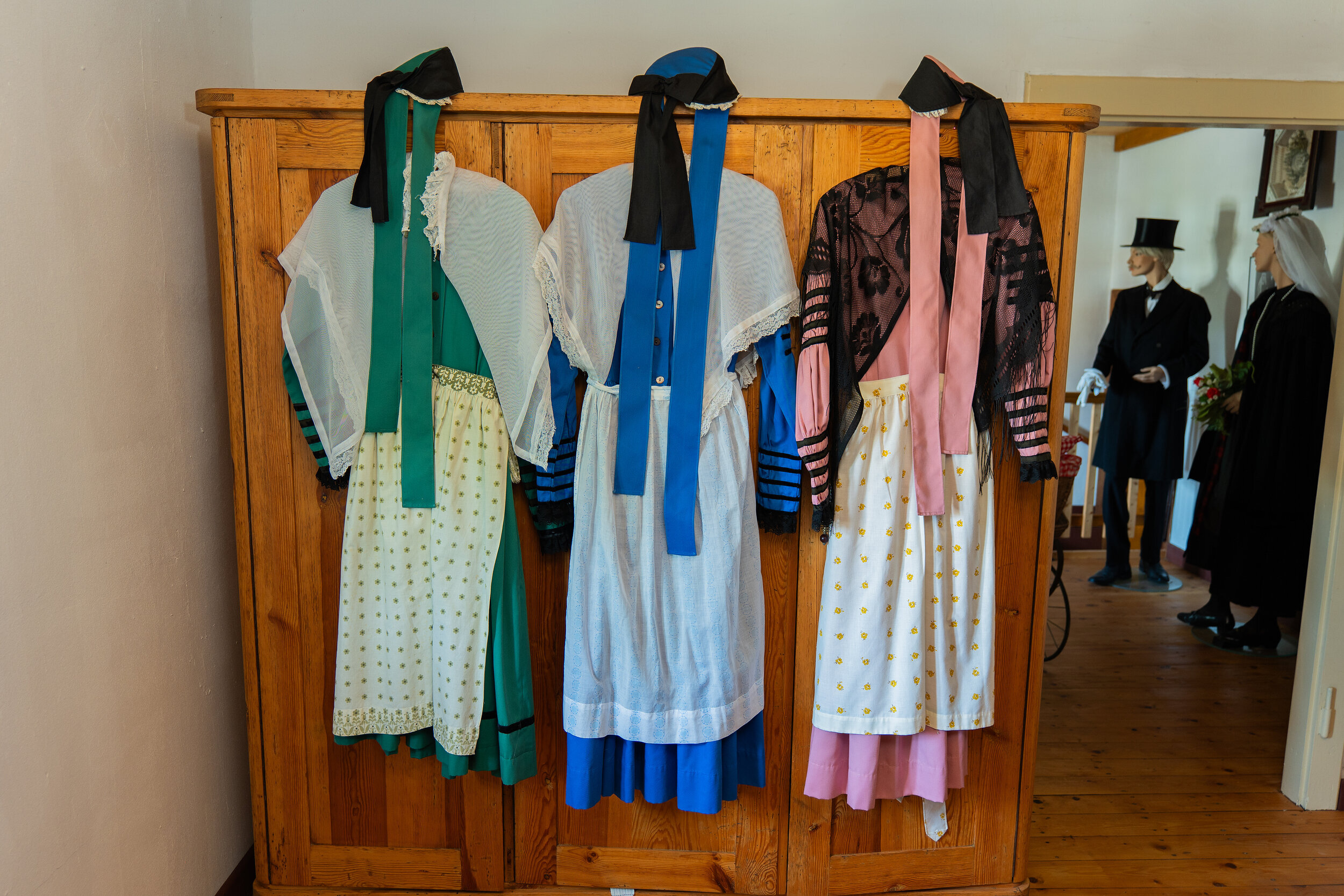Zu sehen sind die traditionellen Trachten der historischen Senne. Für die jungen Mädchen kürzere Kleider mit grün, blau und rosa als Schmuckfarbe, für ältere , verheiratete Frauen die schwarze, lange Tracht.