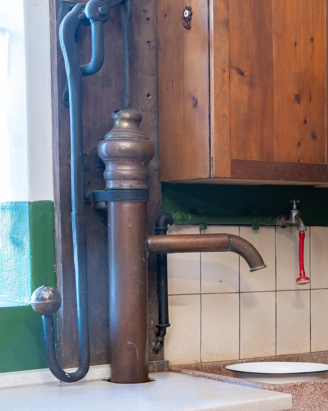 Zu sehen ist eine gusseiserne Wasserpumpe in einer alten Küche.