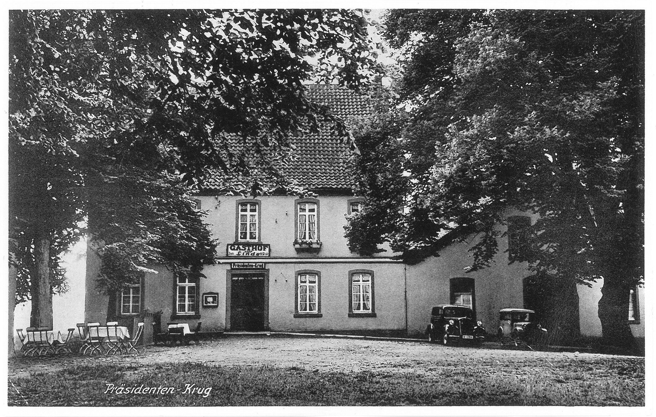 Ein zweistöckiges Gebäude, der Gasthof zur Linde, mit Ziegeldach, weißen Wänden und einem Schild mit der Aufschrift "Gasthof" ist von Bäumen und einer Rasenfläche umgeben, im Vordergrund ist eine Schwarz-Weiß-Fotografie des Gebäudes zu sehen.